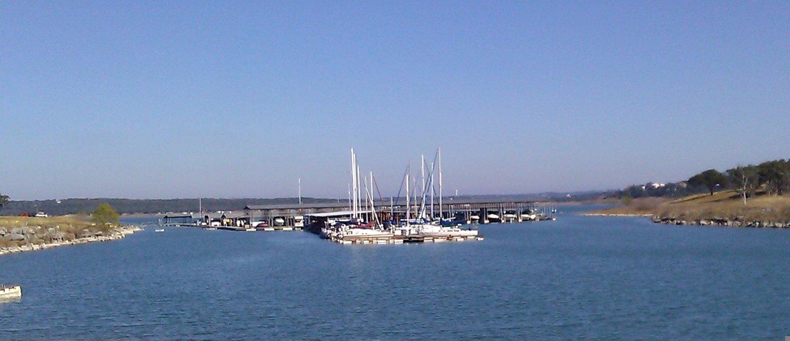 Sailboats moored in covered slips at a Canyon Lake marina under a clear blue sky
