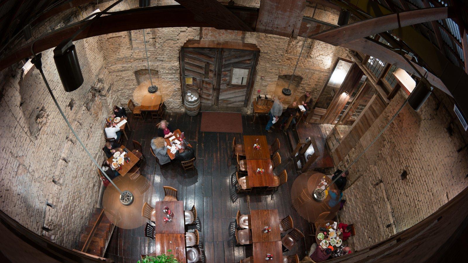 The interior of the Gristmill restaurant inside old cotton-gin ruins — exposed limestone walls, dark wood floor, and rustic tables
