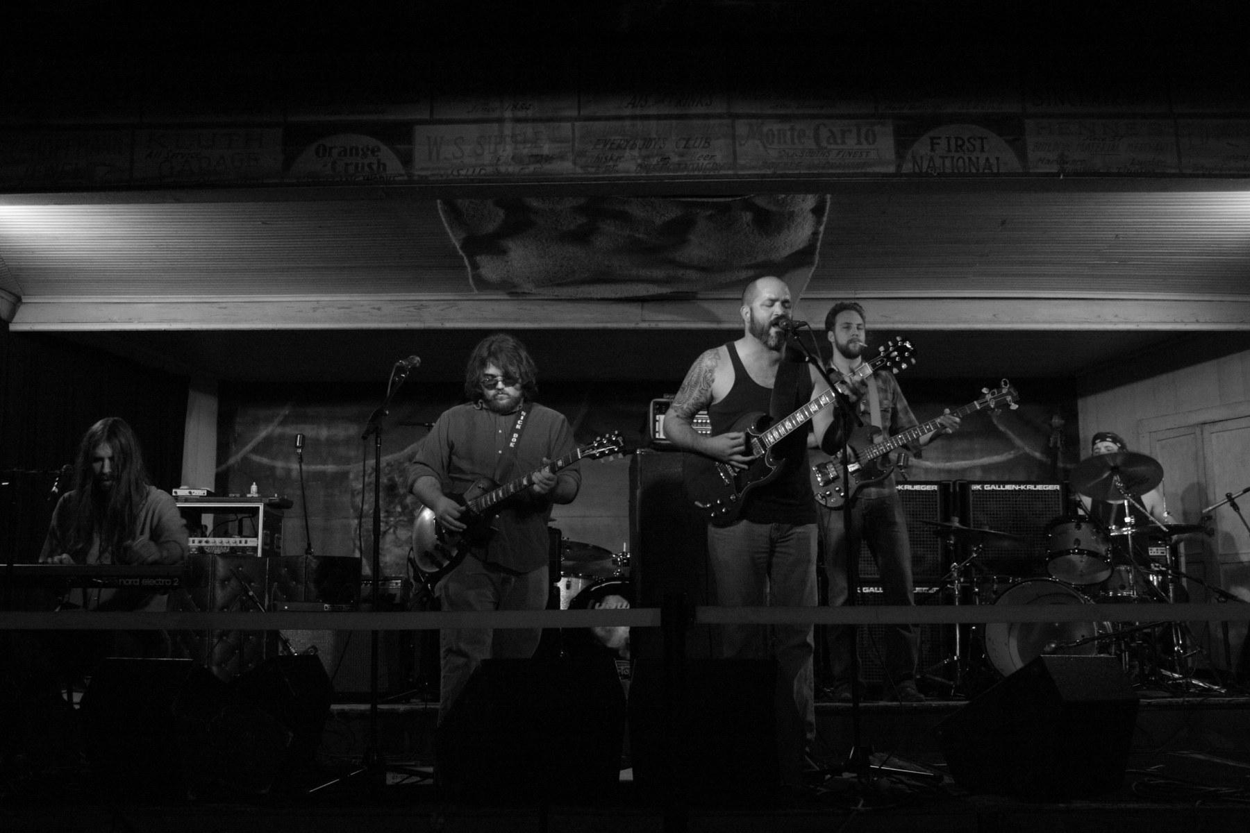 A band playing live on the Gruene Hall stage beneath vintage advertising boards