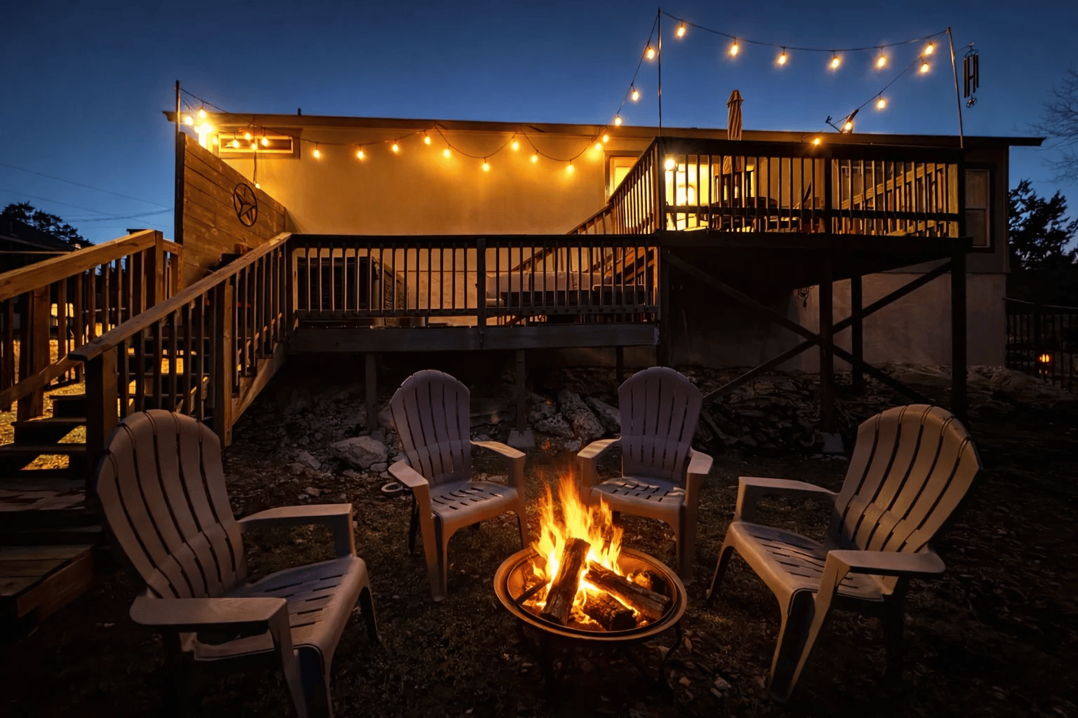 The fire pit burning below the string-lit deck at night